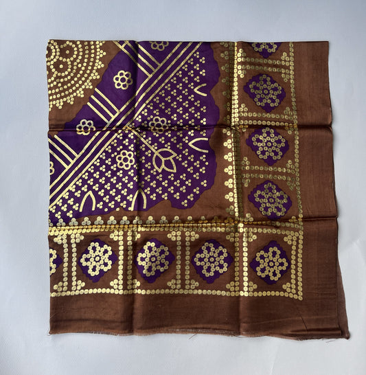 Decorative brown fabric square with purple and gold pattern.