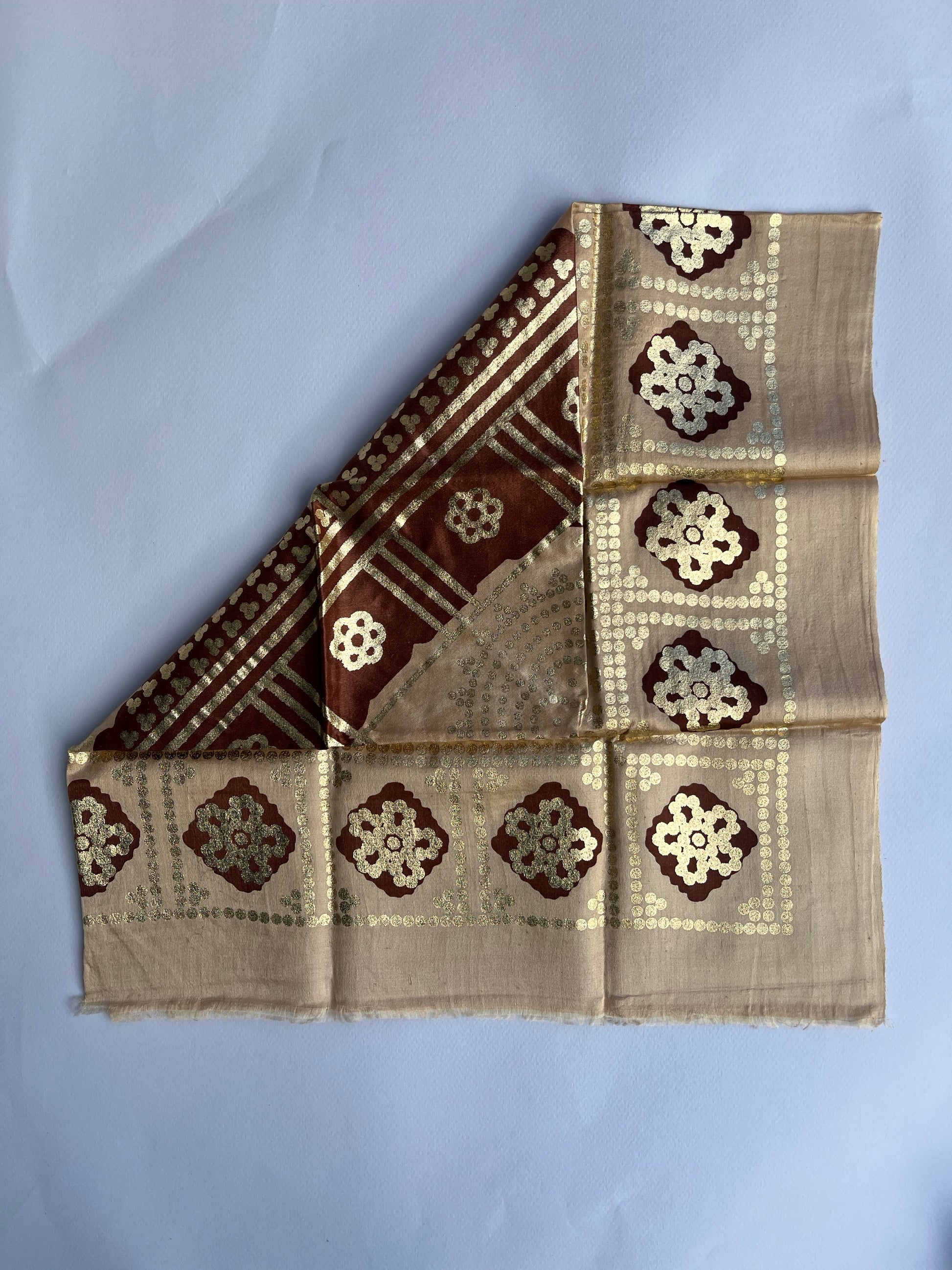 Folded fabric with decorative patterns a beige background.