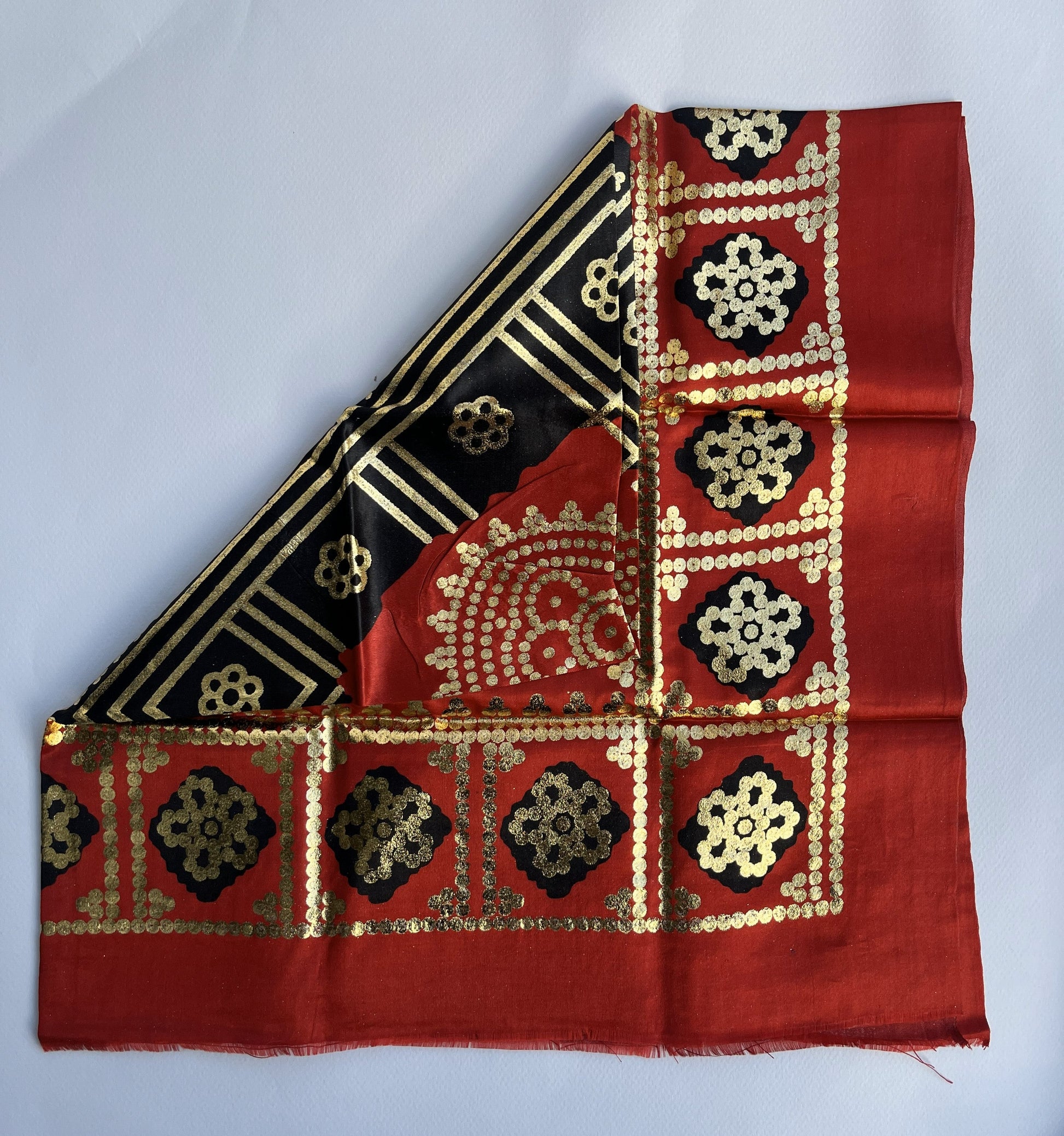 Red fabric with gold and black pattern. 